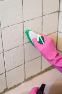 Cleaning mold from bathroom wall tiles to prevent mold growth and moisture damage
